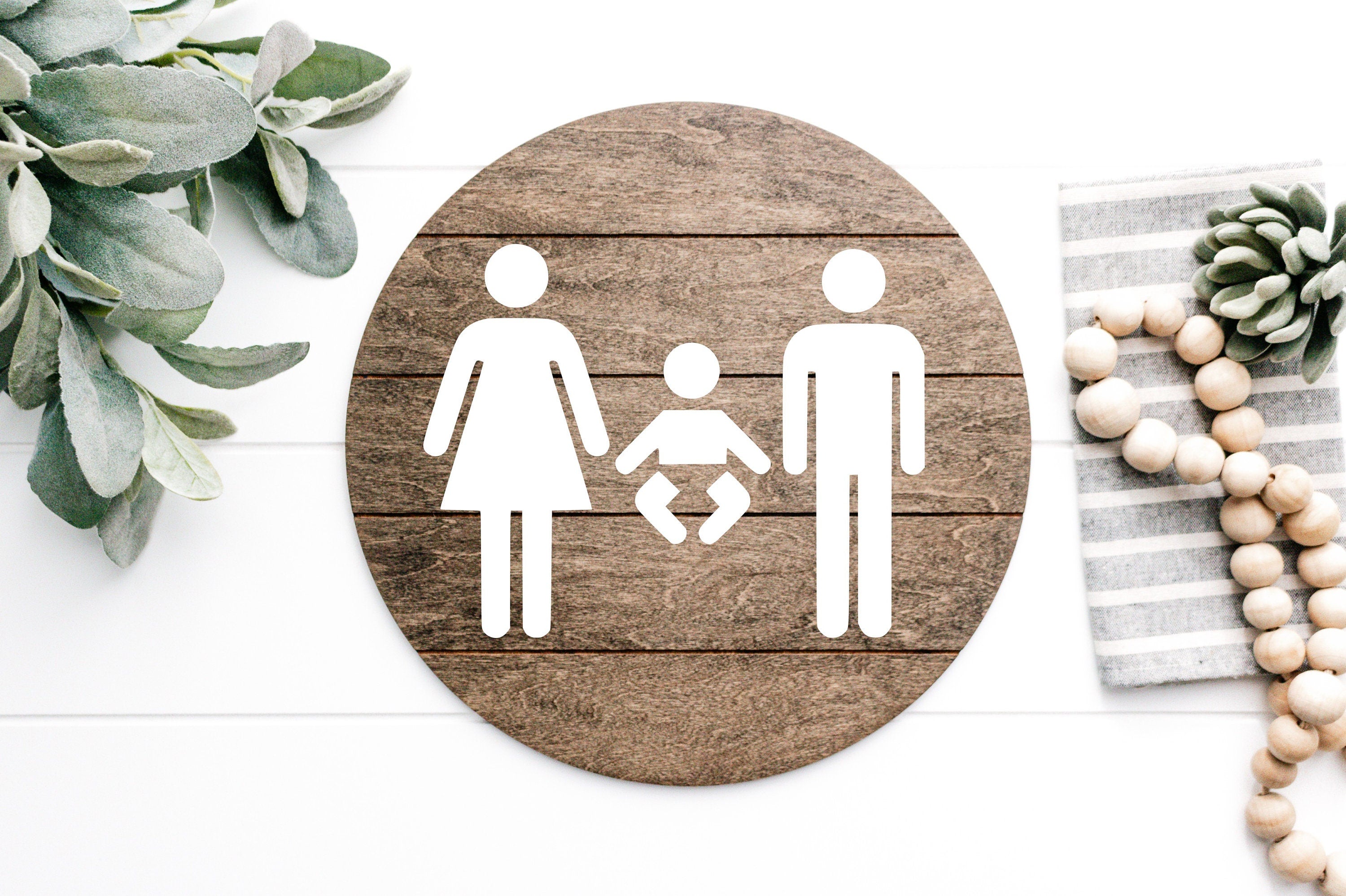 3D restroom changing room sign, round dark wood with white male, female and baby icons
