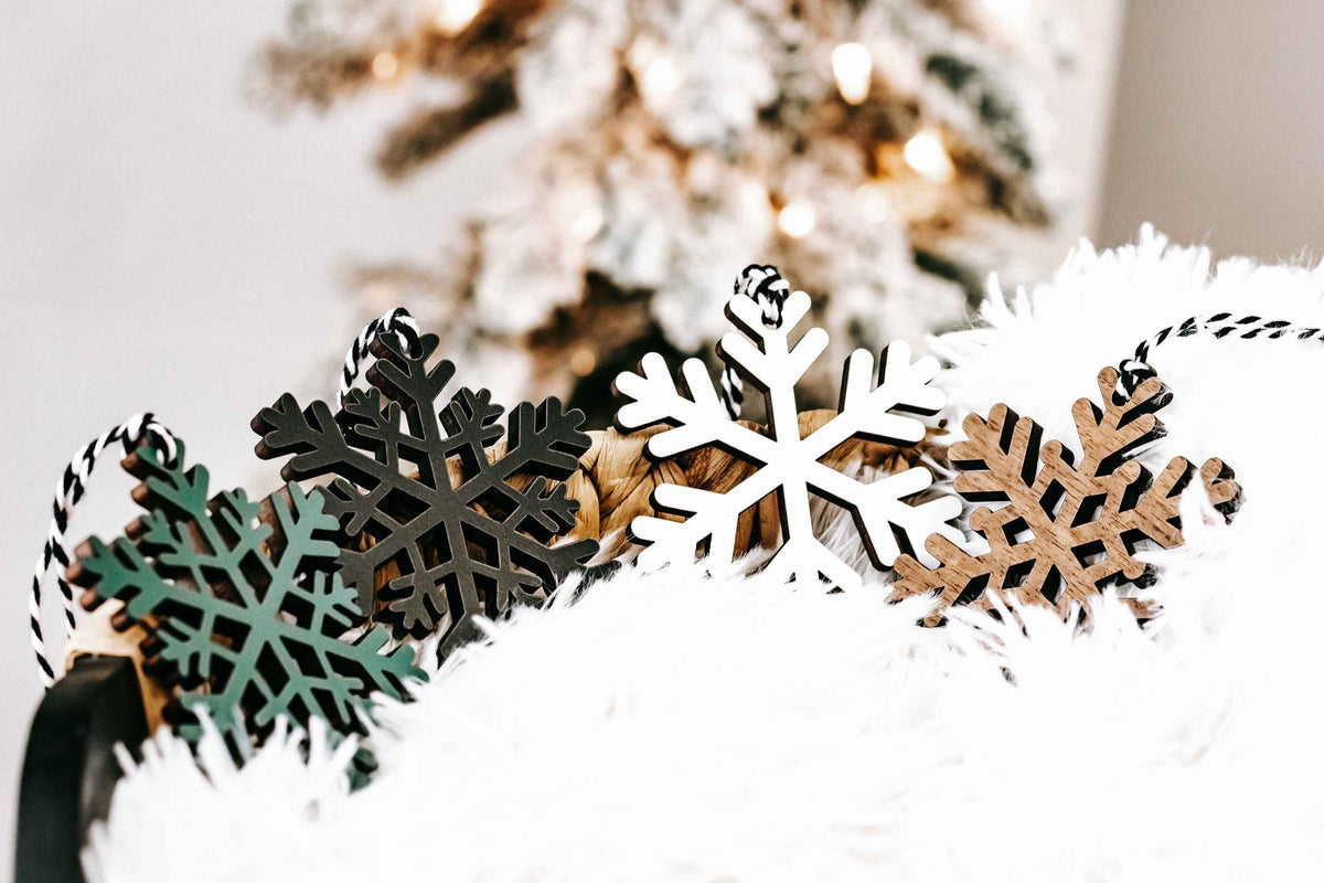 Wooden snowflake ornaments in dark, natural wood, and white tones with hanging loop tops