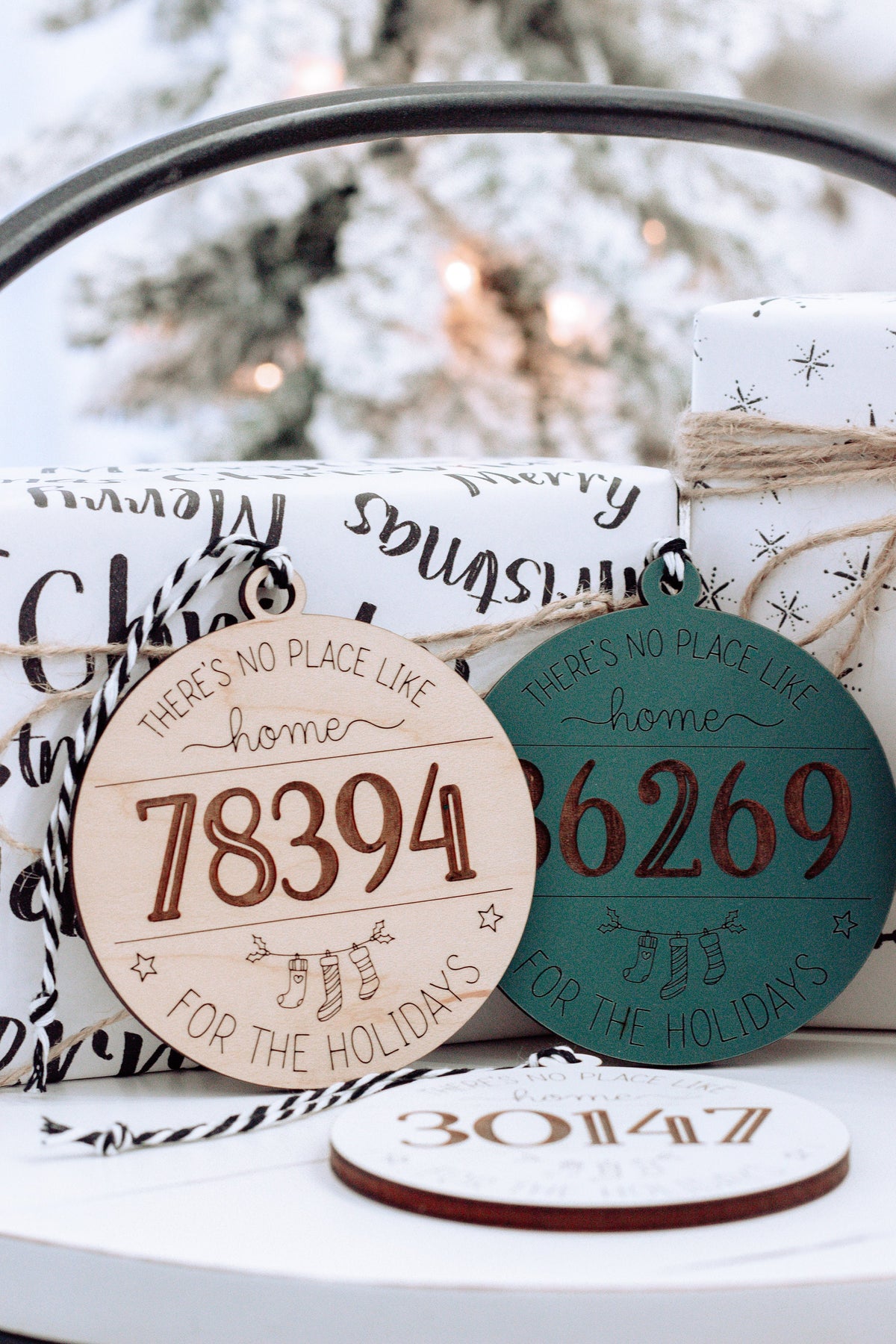 Teal and white personalized home holiday ornaments with zip codes “78394” and “66269” in view.