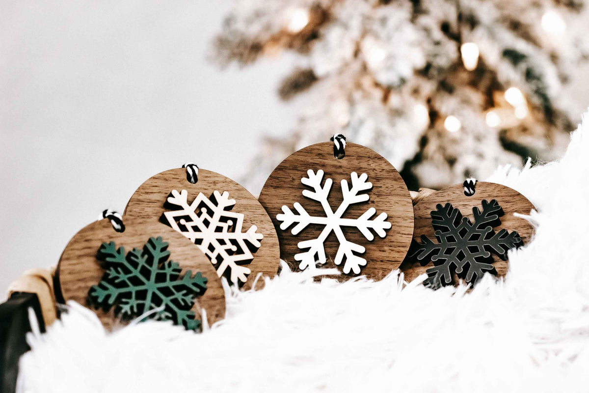 Set of round wooden snowflake ornaments with striped hanging loops in white, green, black