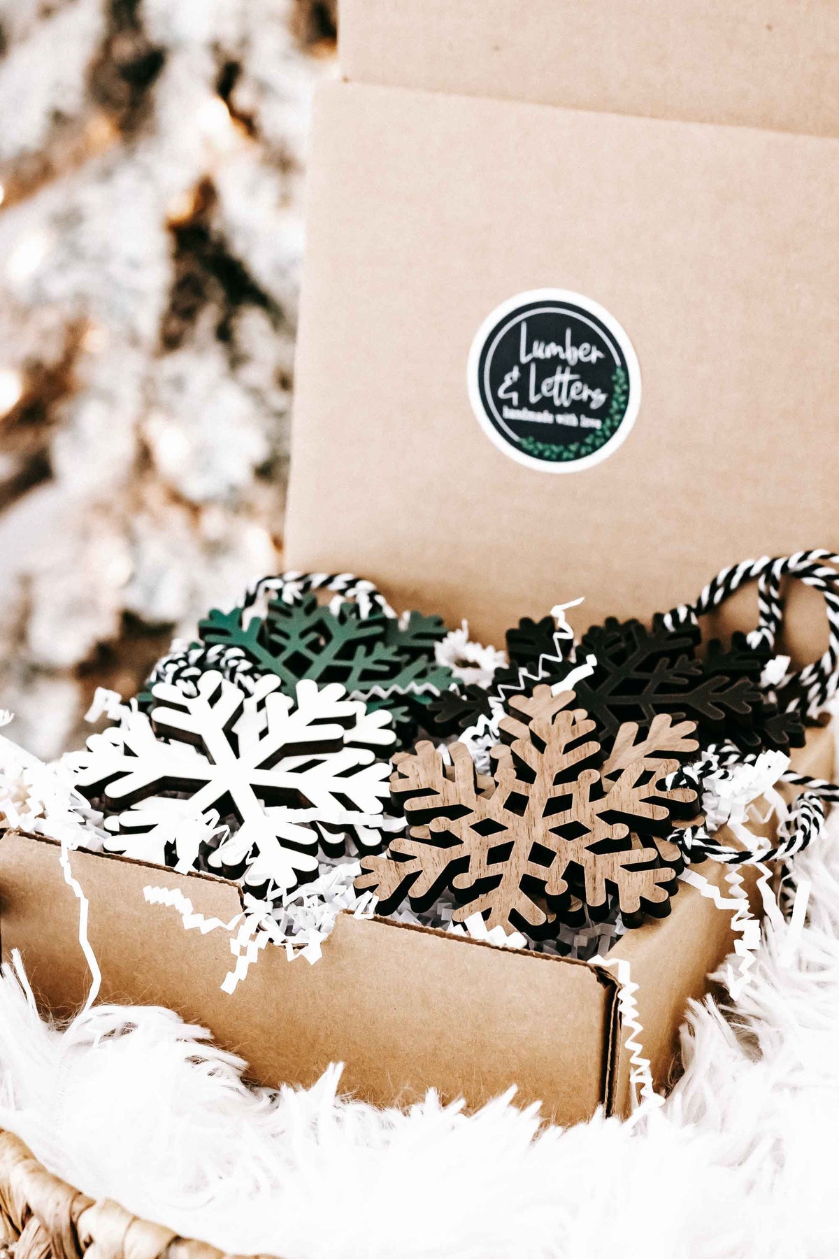 Kraft box with wooden snowflake ornaments in dark, green, and natural wood, string hangers