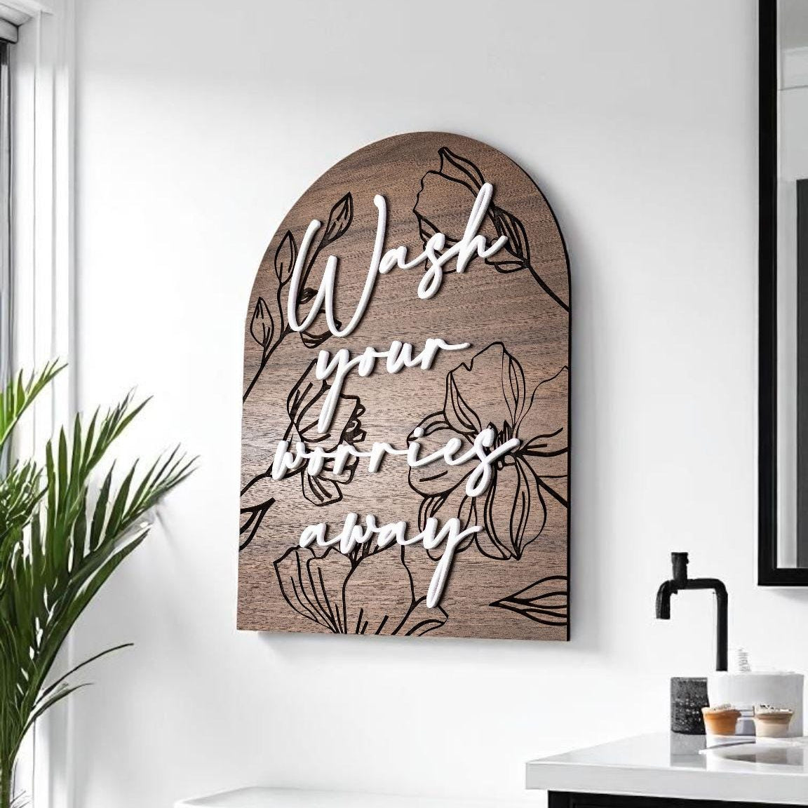 Floral engraved arch wall sign in dark brown with black “Wash your worries away” text