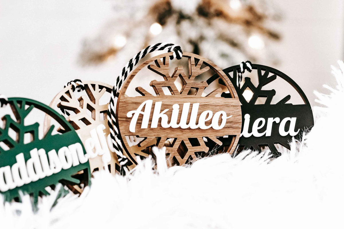 Personalized snowflake ornaments with tan and black round tags and white script names