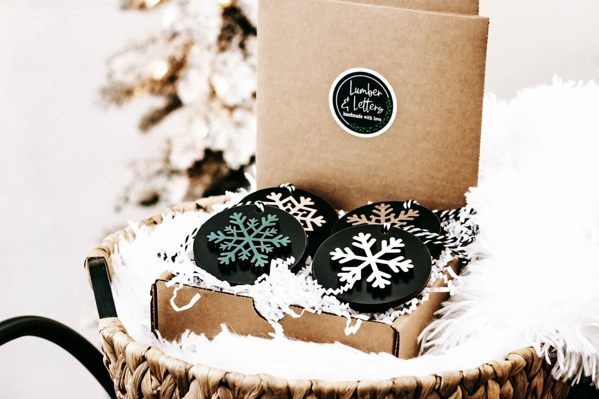 Set of 8 black wooden snowflake ornaments in a kraft gift box with white faux-fur