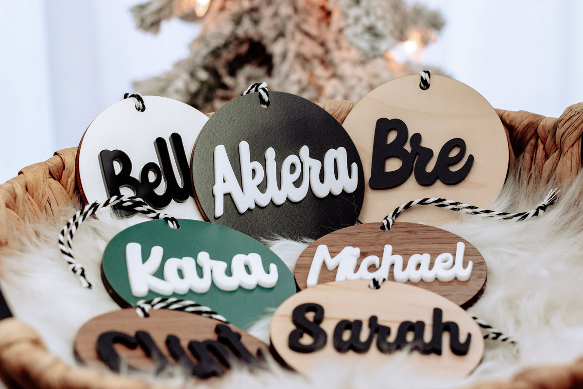 Round wooden name ornaments with rope hangers and teal, black, and tan lettering