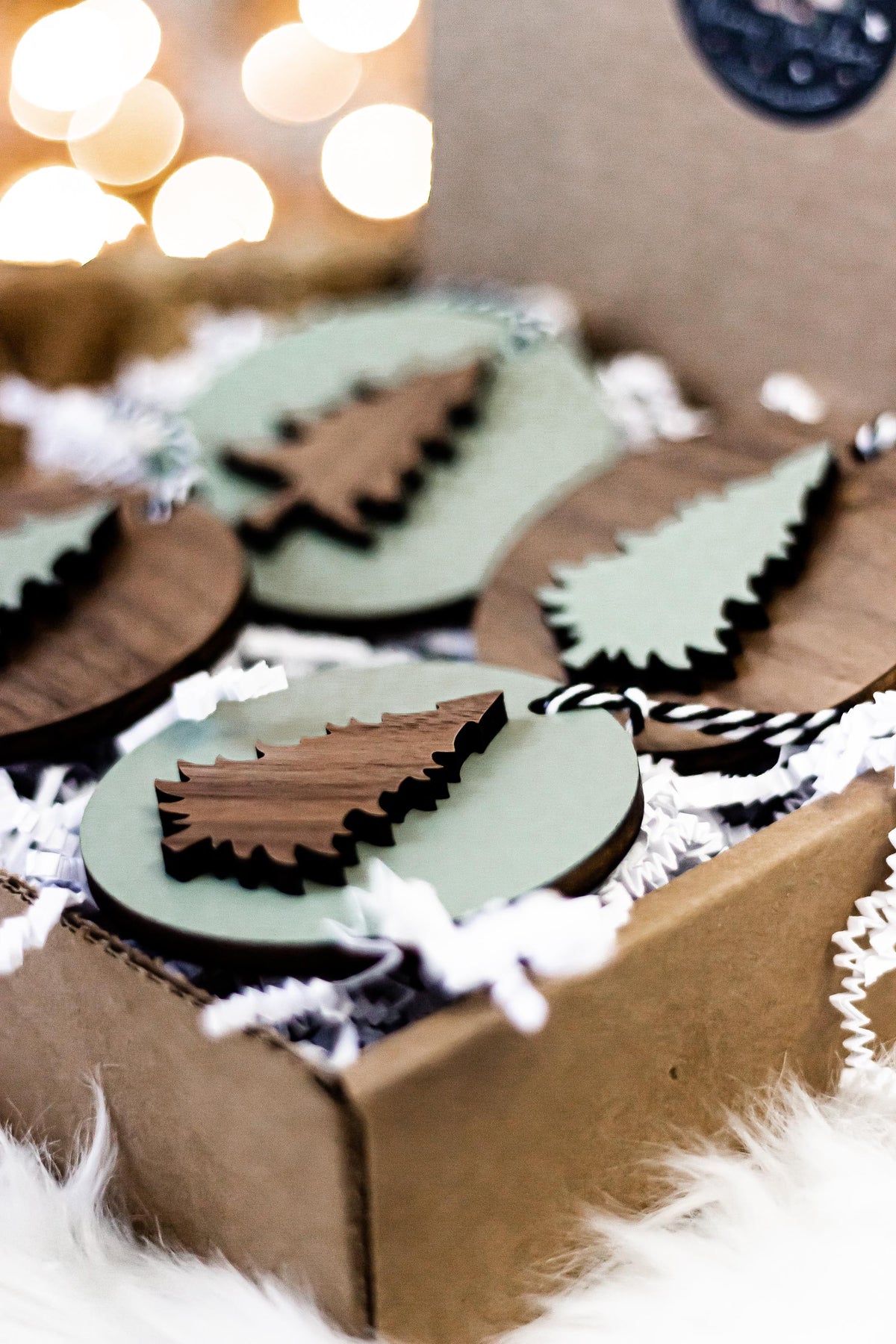Wooden Christmas tree ornaments with cutout trees and striped cords in the box