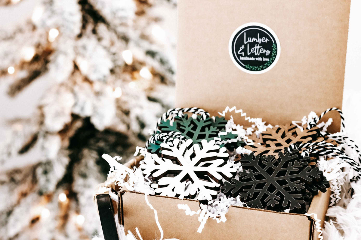 Wooden snowflake ornaments in kraft box with dark, white, and natural wood shapes