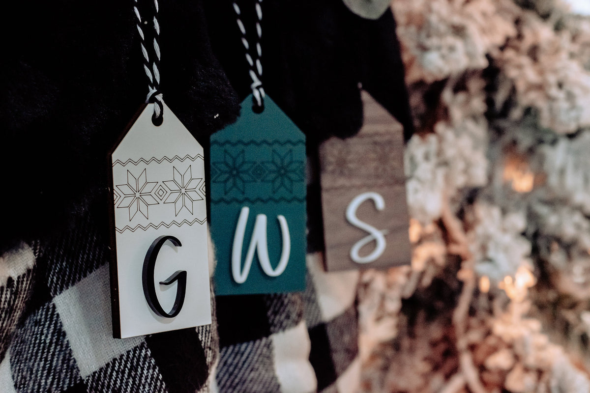 Close-up of personalized stocking tags with letters G, W, and S in Nordic patterns
