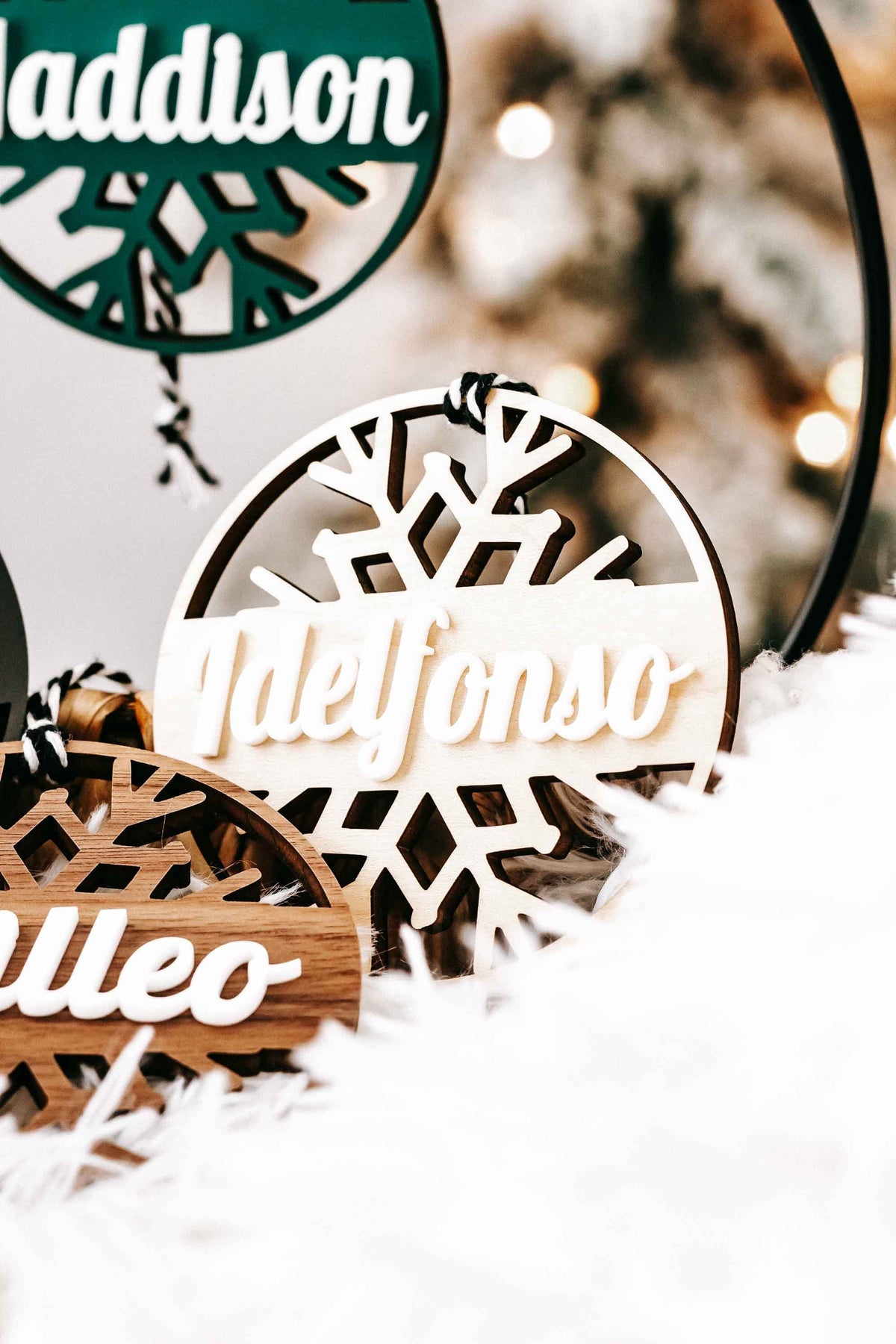 Personalized snowflake ornaments with white and black round tags and white script names