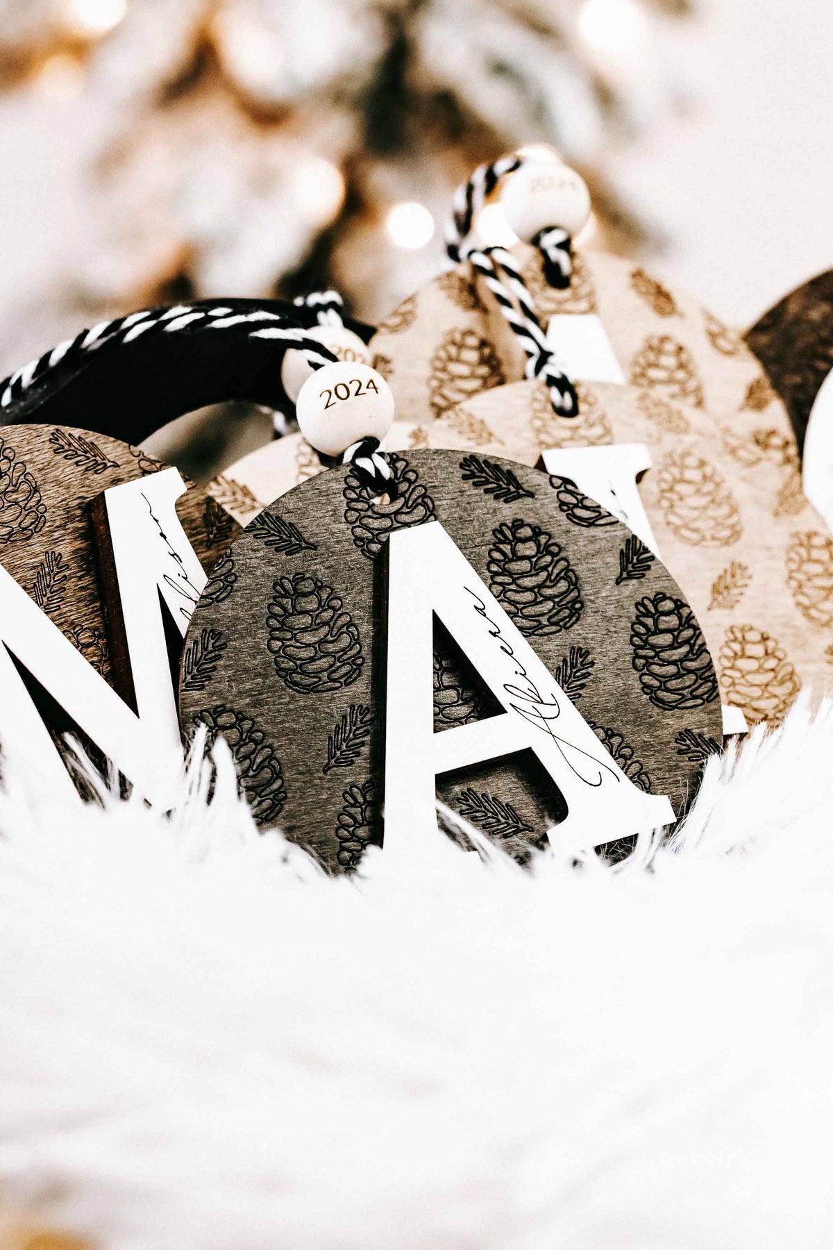 Round engraved pine cone ornament with letter N, zebra-striped cord, year 2024 tag