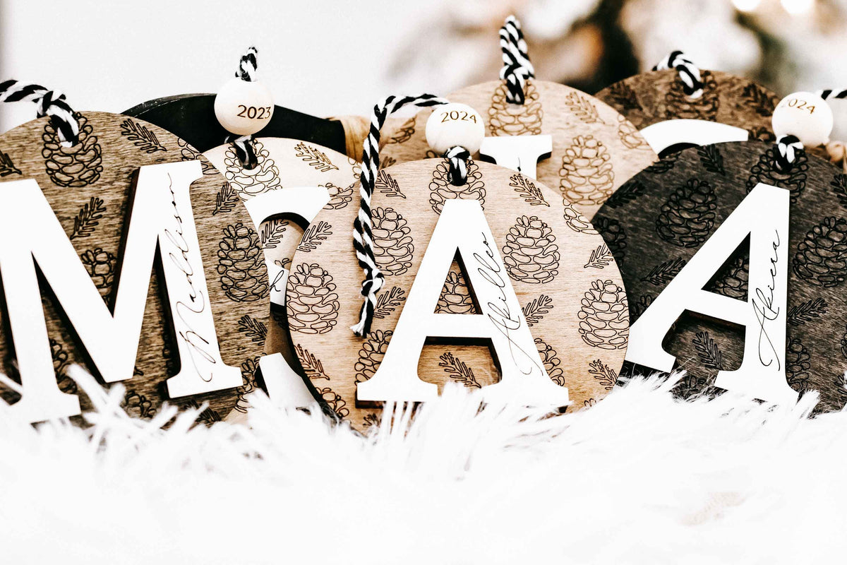 Set of round engraved pine cone ornaments with zebra-striped loops and year tags 2024