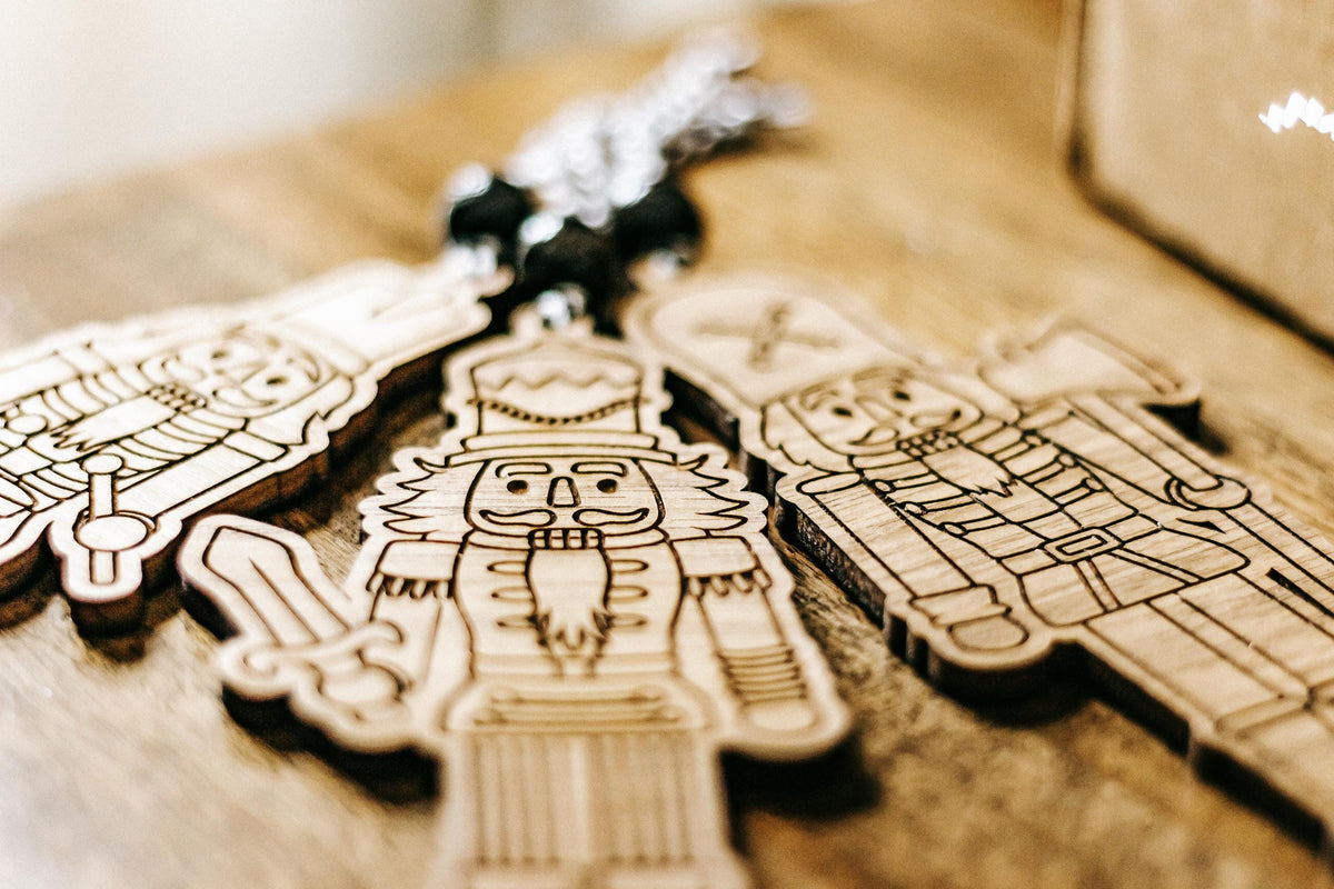 Close-up of engraved wooden nutcracker ornaments in a gift box with dark bead cords