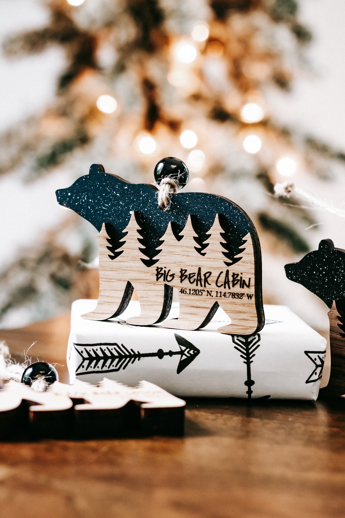 Bear cabin themed ornament with dark teal glitter bear, pine trees, and cabin scene