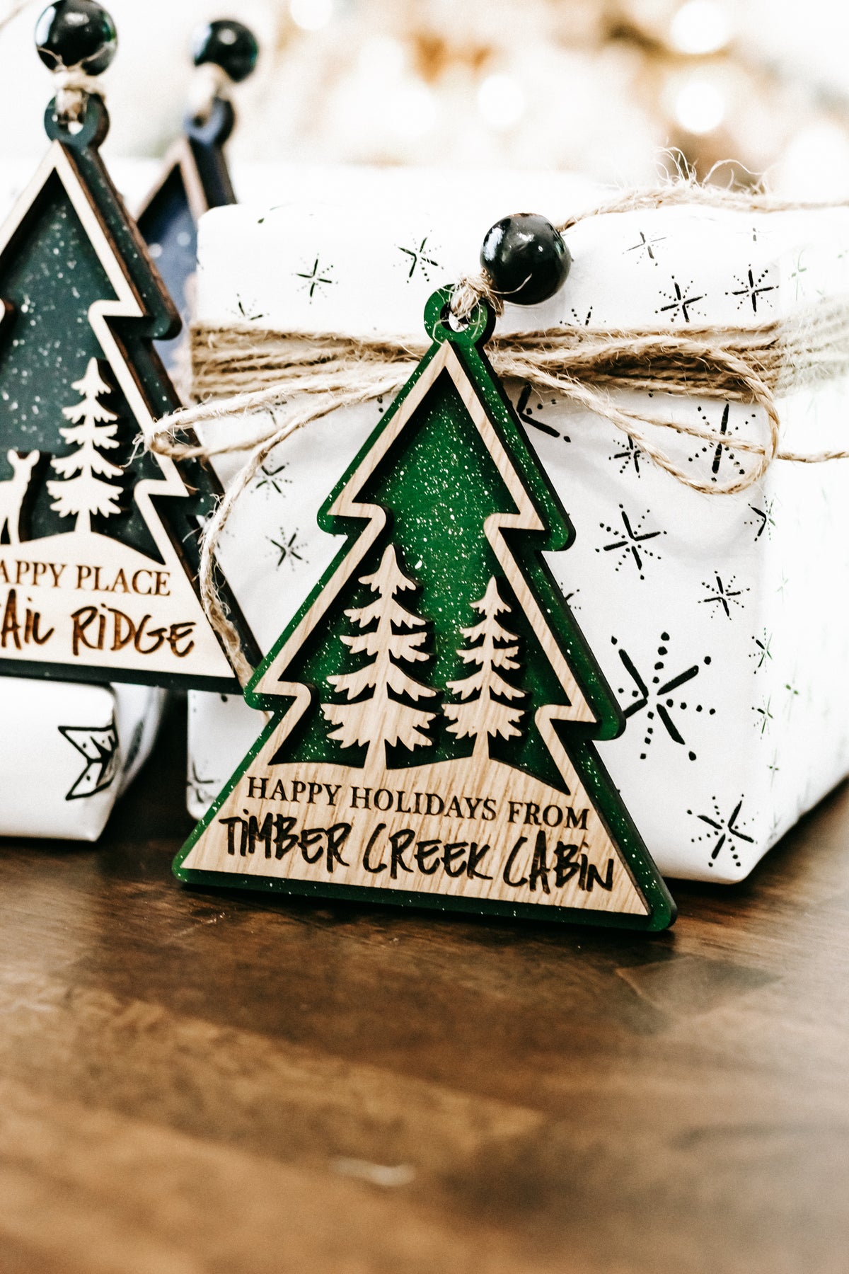 Green hanging tree-shaped ornament with pine illustration and holiday text