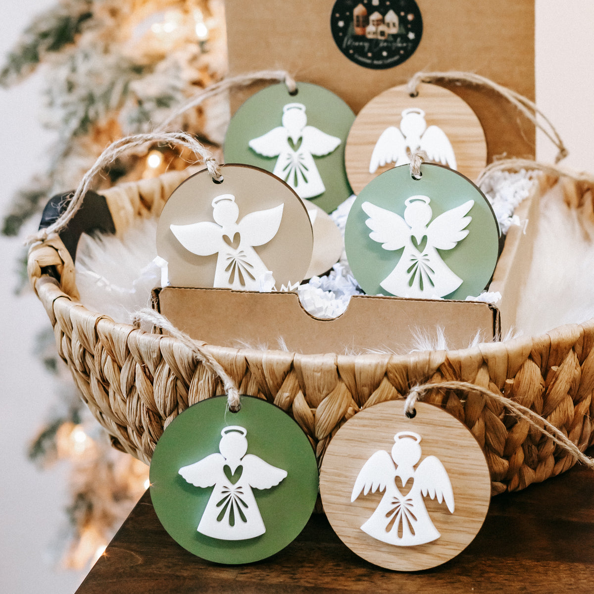 Close view of round angel ornaments in green and wood, white angel figures, twine hanging