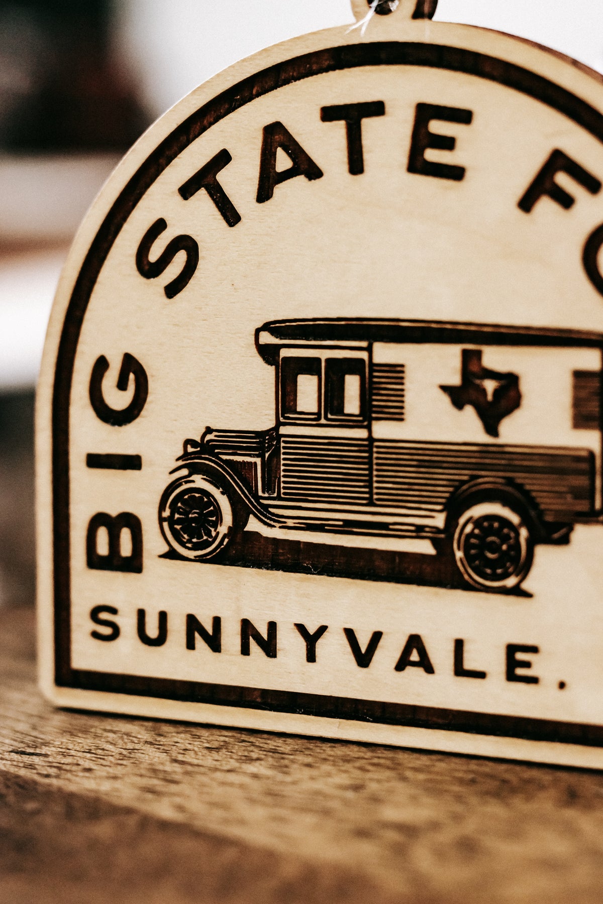 Wooden ornament close-up with van graphic and “BIG STATE FOODS / Sunnyvale” lettering.