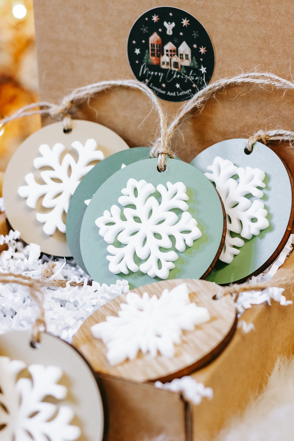 Assorted round wooden snowflake ornaments with green and wood tones, white cutouts, twine hangers