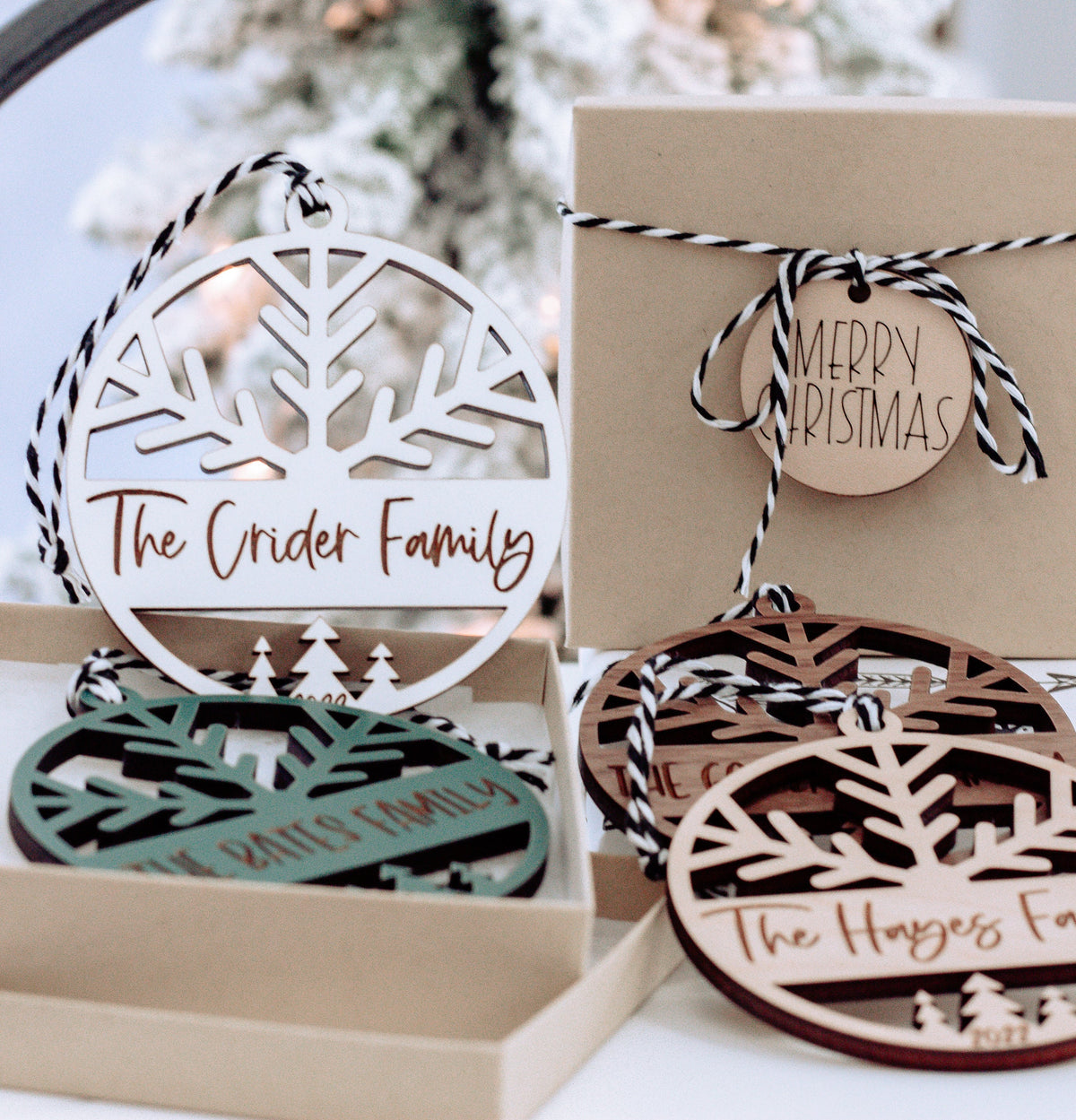 Round engraved family name Christmas ornaments with tree and snowflake cutouts, in gift box