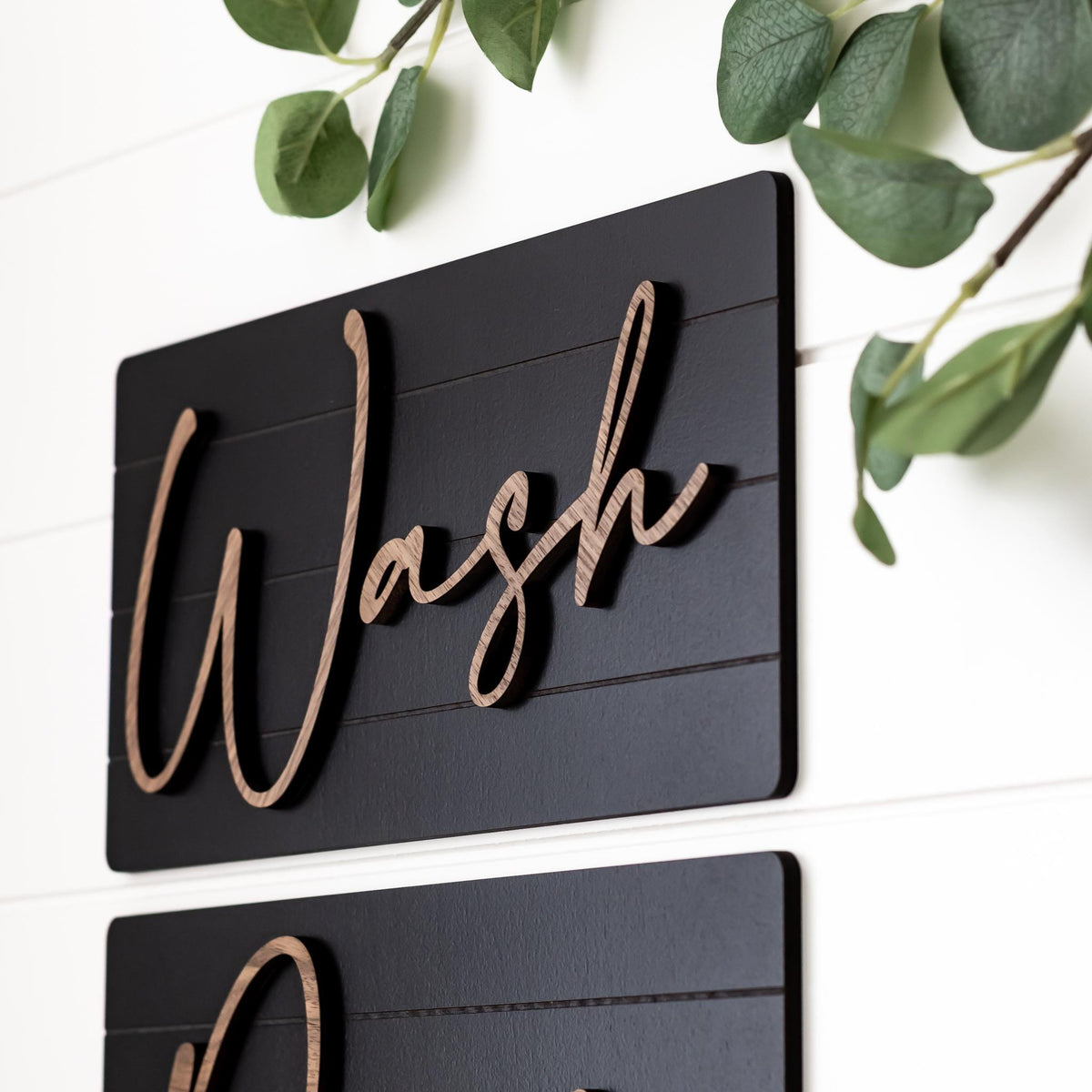 Detail view of dark wall sign panel with wood-tone cursive lettering, Wash and Dry style