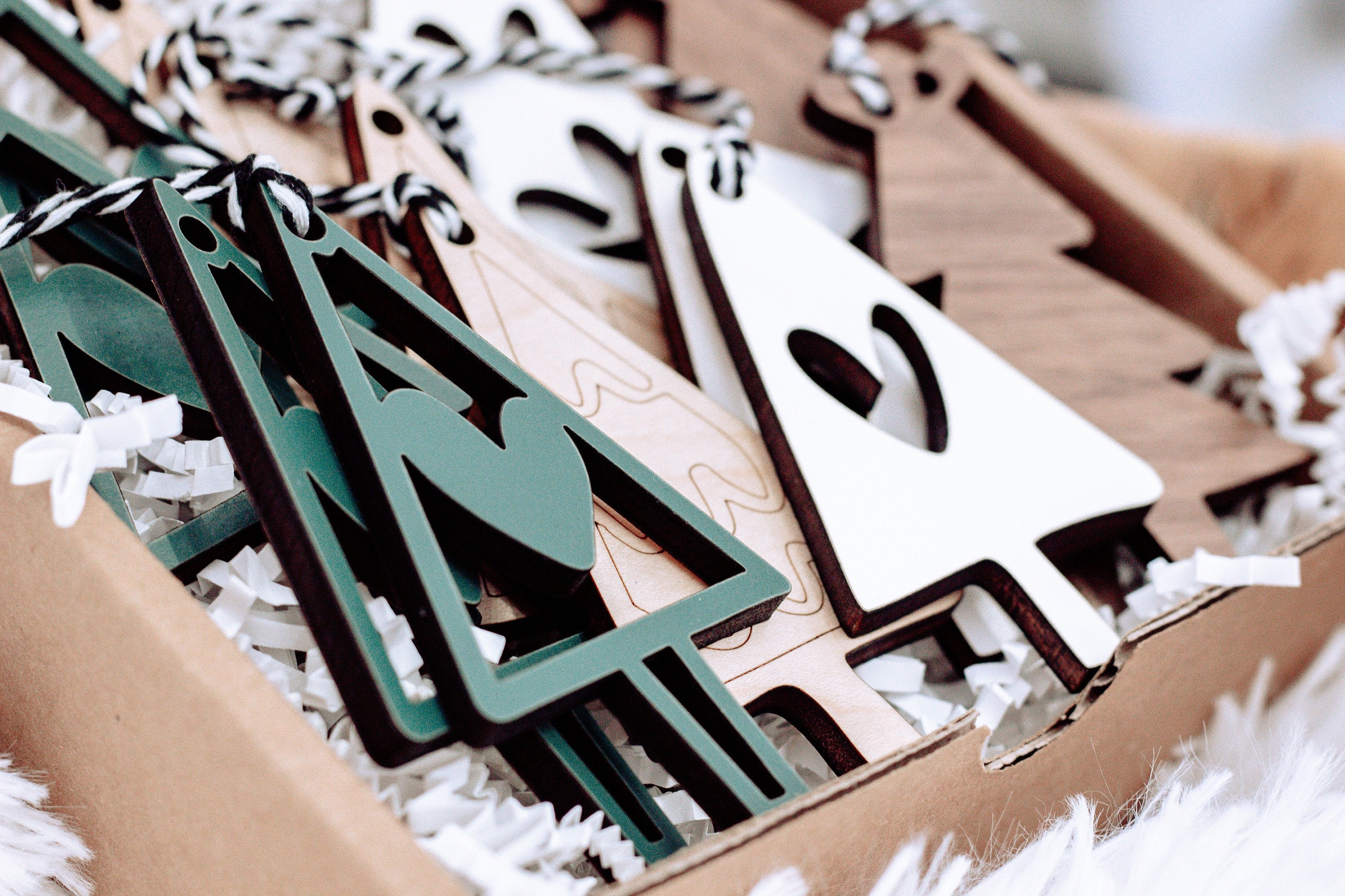 Wooden Christmas ornaments in a box: green and white tree shapes with striped string loops