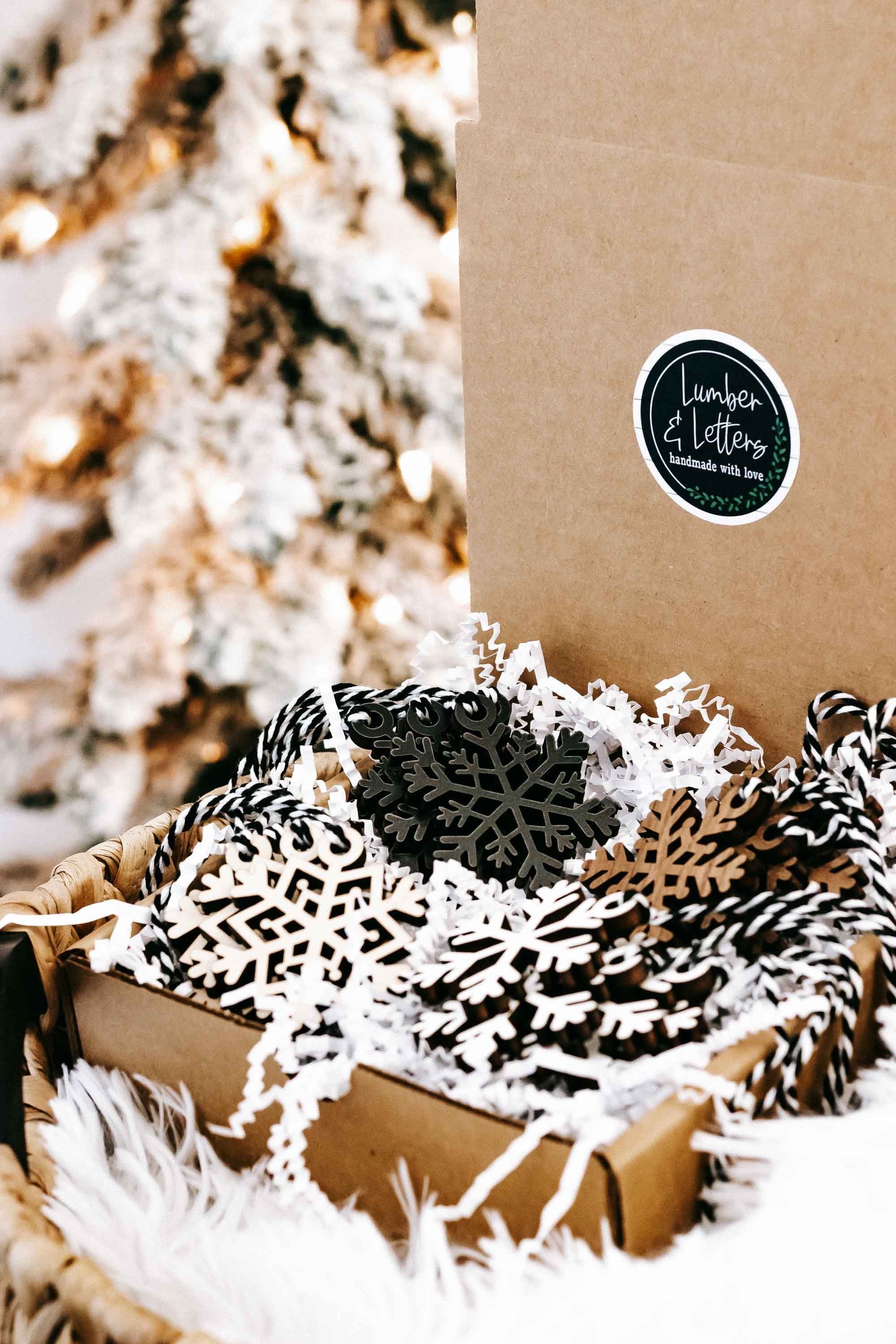 Snowflake wooden ornaments in kraft packaging with round label and black and beige cutout designs