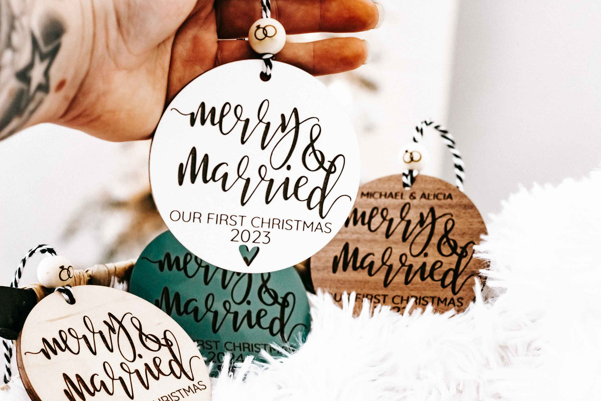 Set of round “Merry & Married” Christmas ornaments held in hand, with year details