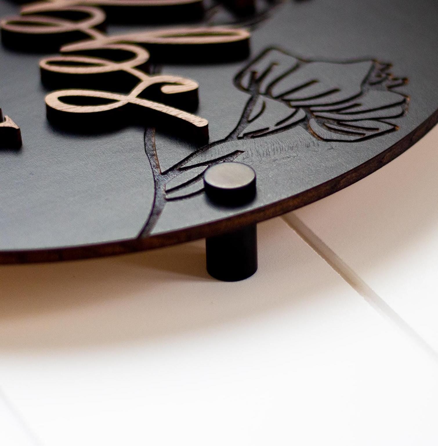 Wood directional restroom sign detail with engraved icons and small round mounting bump