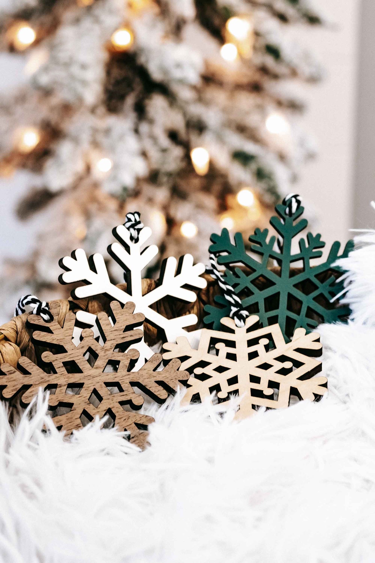 Set of snowflake wood Christmas ornaments in white and dark green on white faux fur