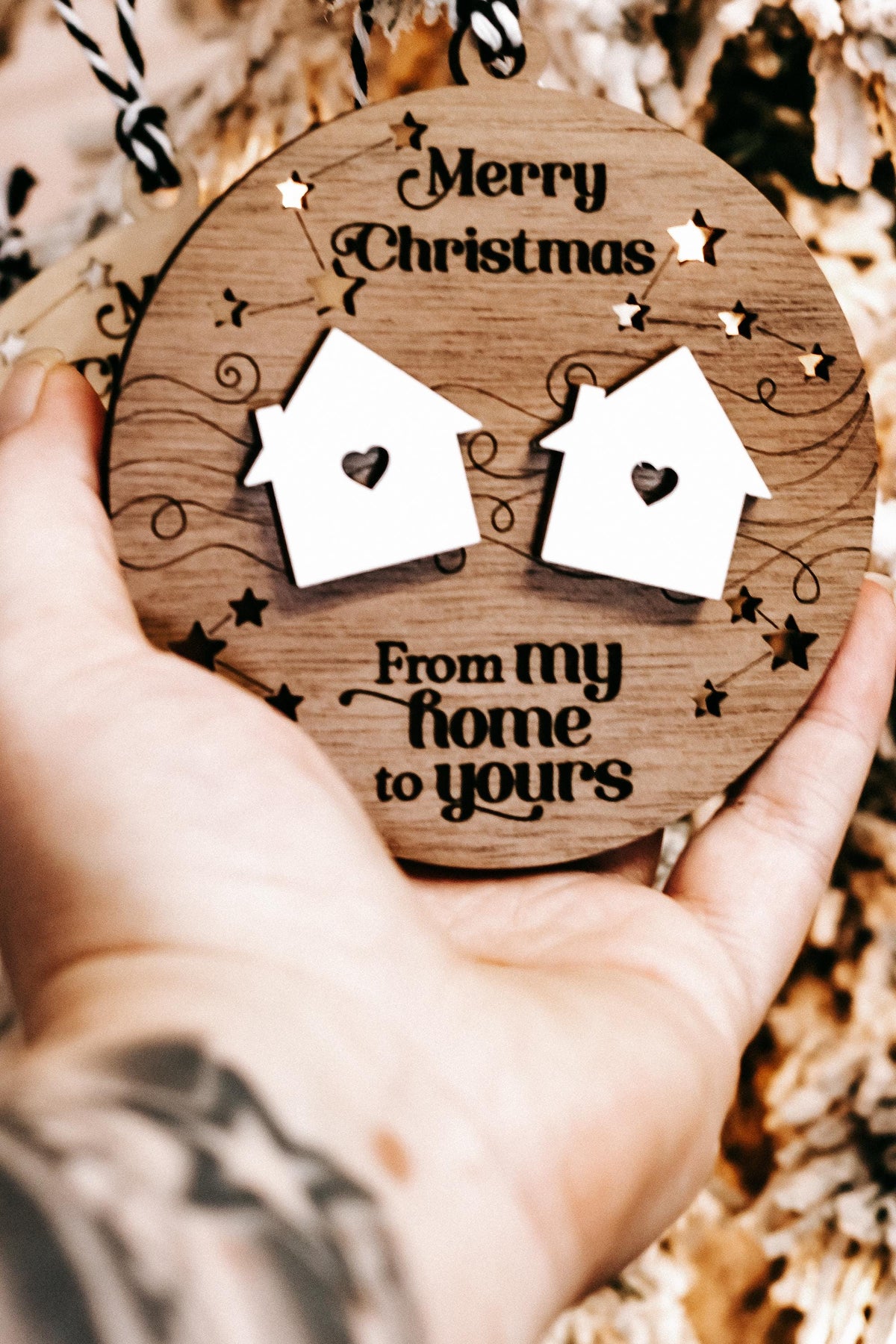 Handheld round wooden “Merry Christmas” ornament with two white house icons and stars