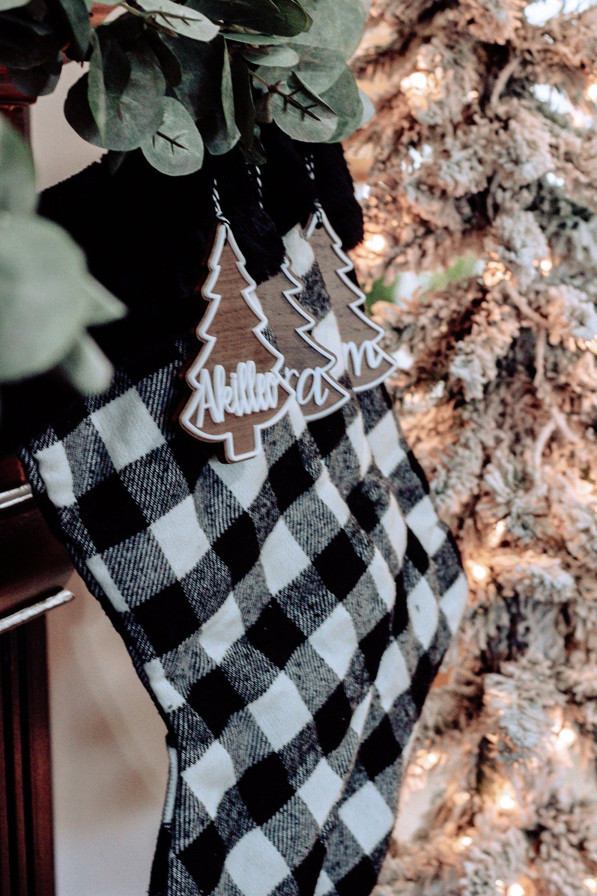 Personalized Christmas tree ornament tags hanging on buffalo plaid stocking
