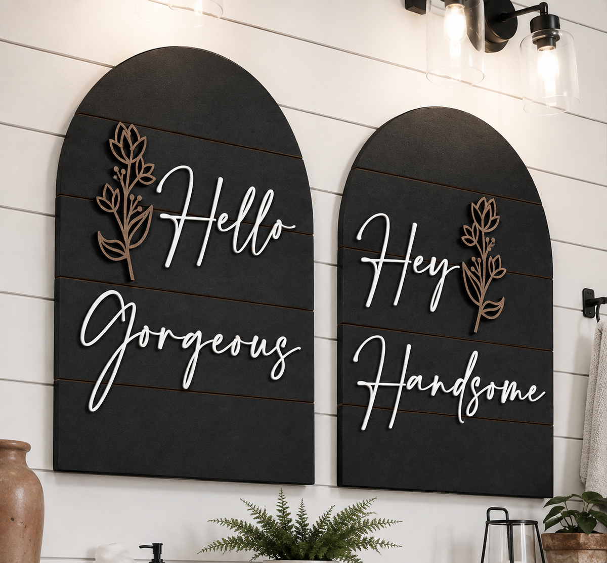 Two black arched wall signs with gold leaf details and white cursive text: Hello Gorgeous, Hey Handsome