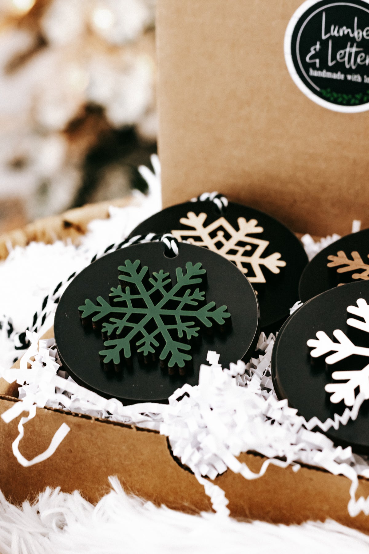 Black wooden ornament discs with green snowflakes and tan accents, hanging loops