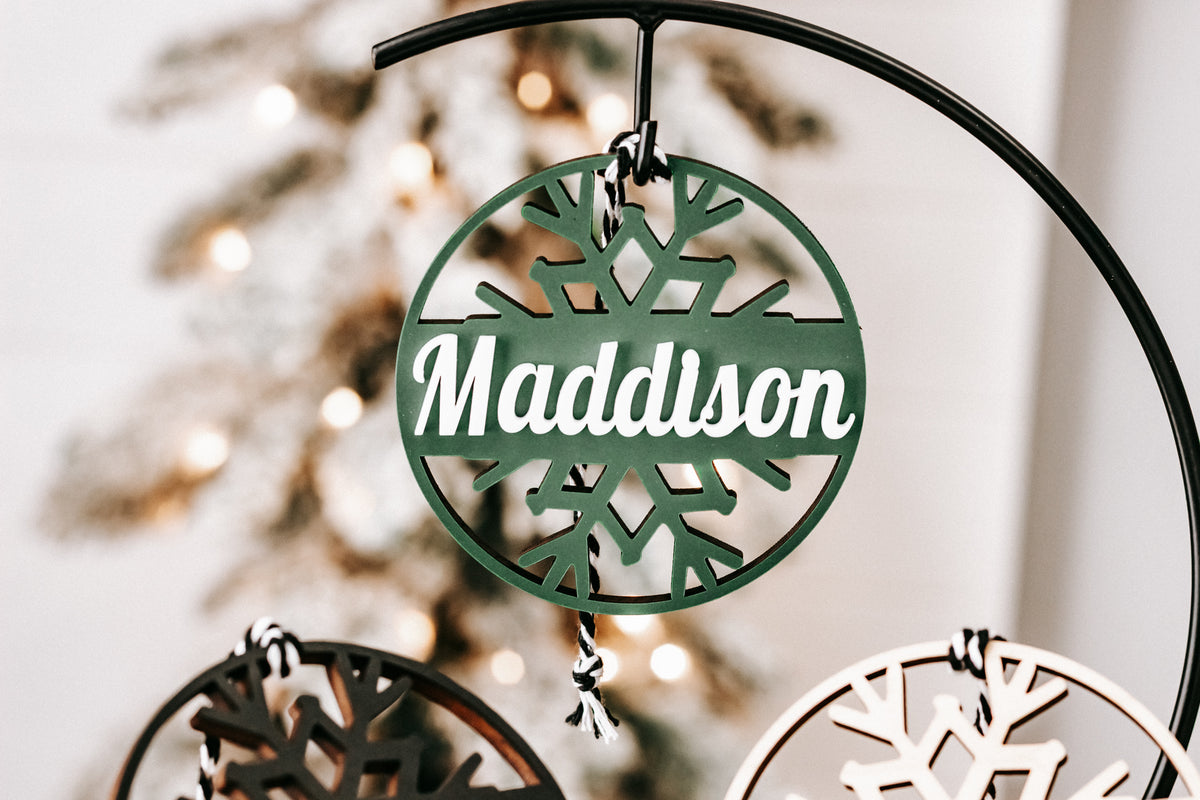 Round green snowflake ornament engraved “Madison” with black hanging frame