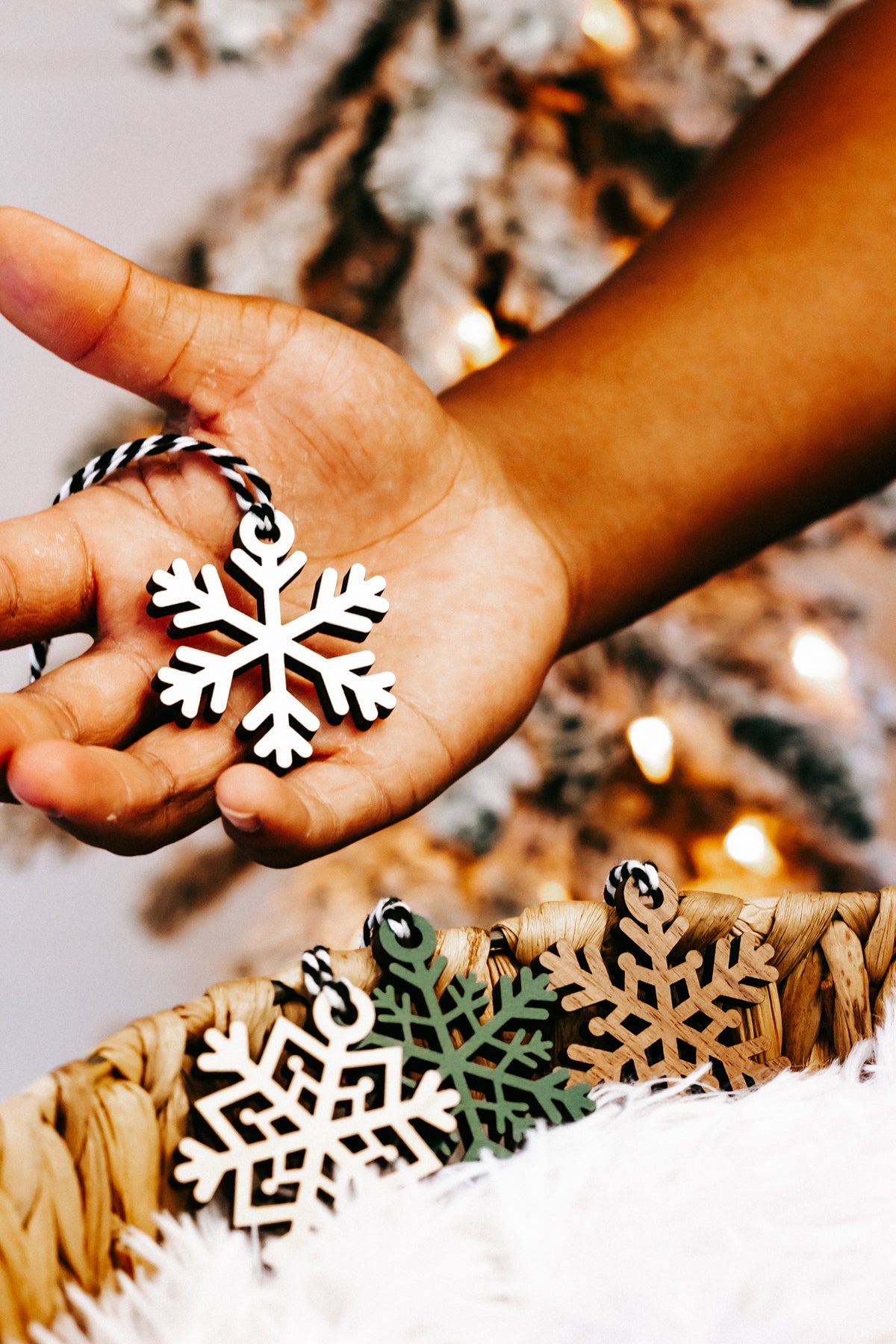Hand holding a mixed-color snowflake ornament with braided string loop