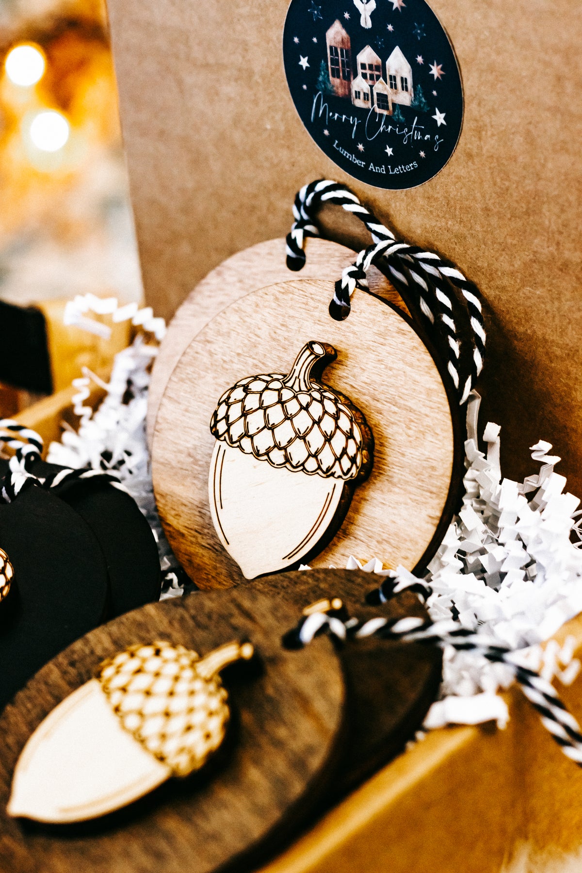 Round acorn ornament detail: wood disc acorn with gold checkered cap, striped twine loop.