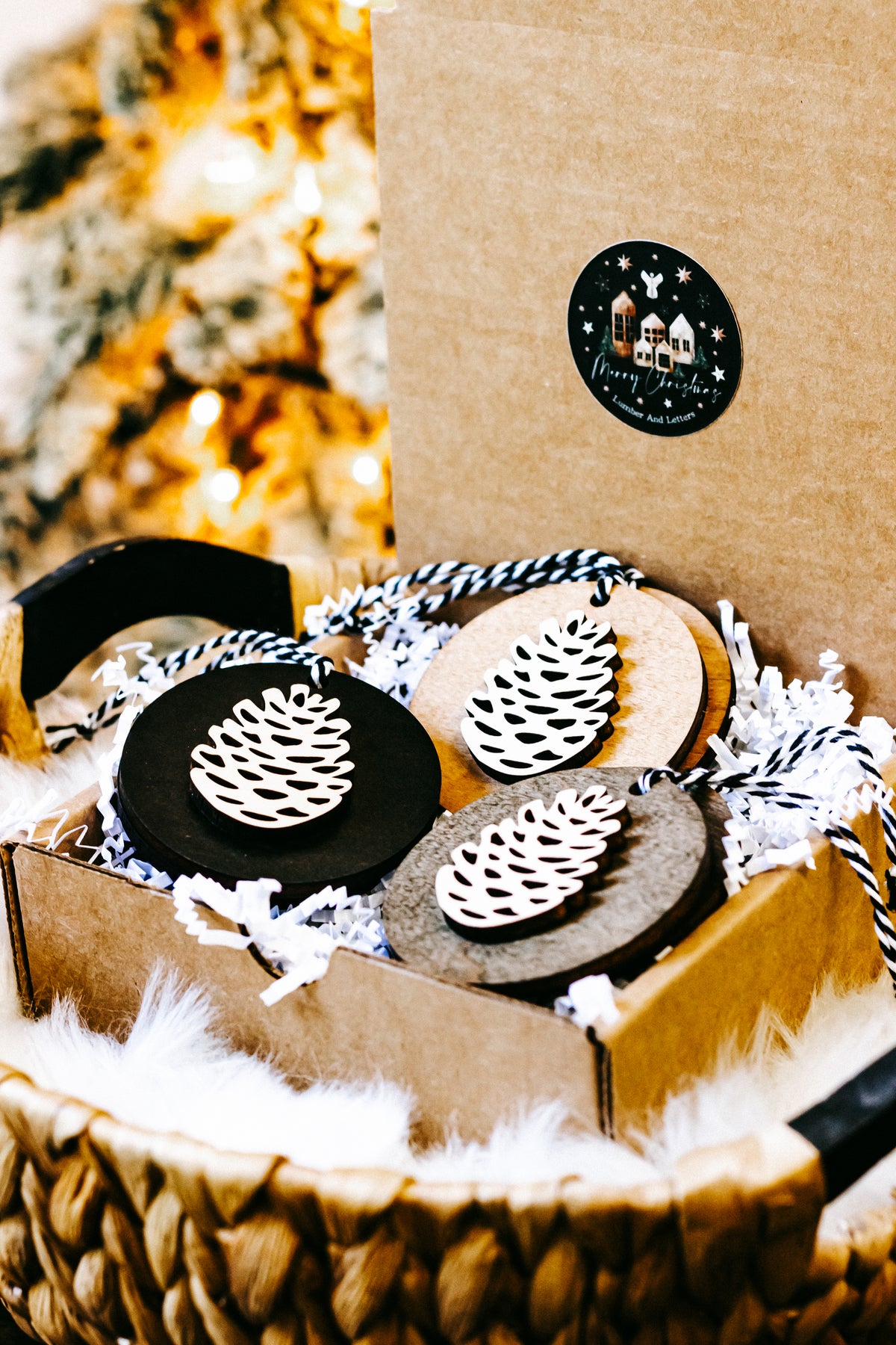 Wooden pinecone ornaments in box, black and natural wood discs with white pinecone cutouts