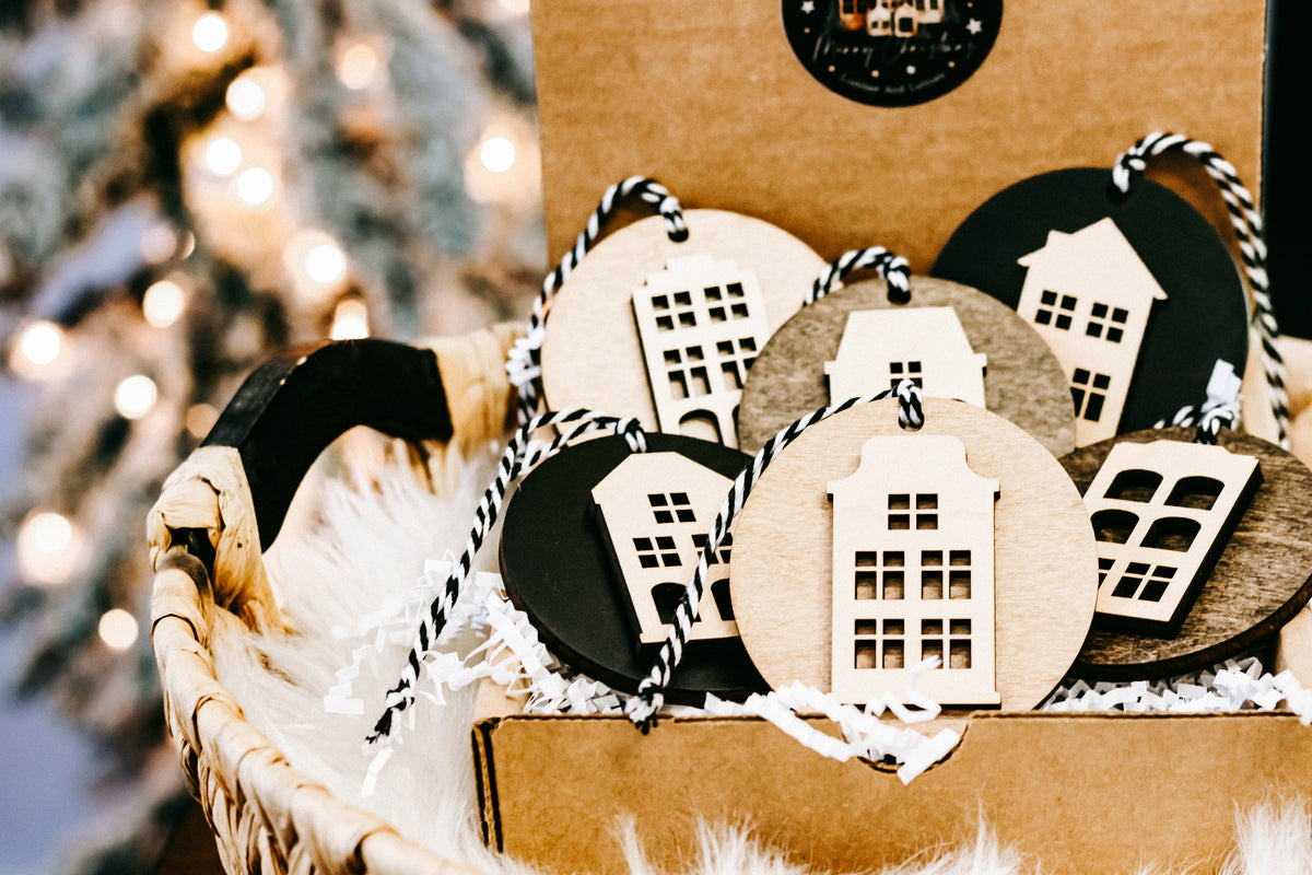 Box of round house ornaments with striped cords and white filler around the discs