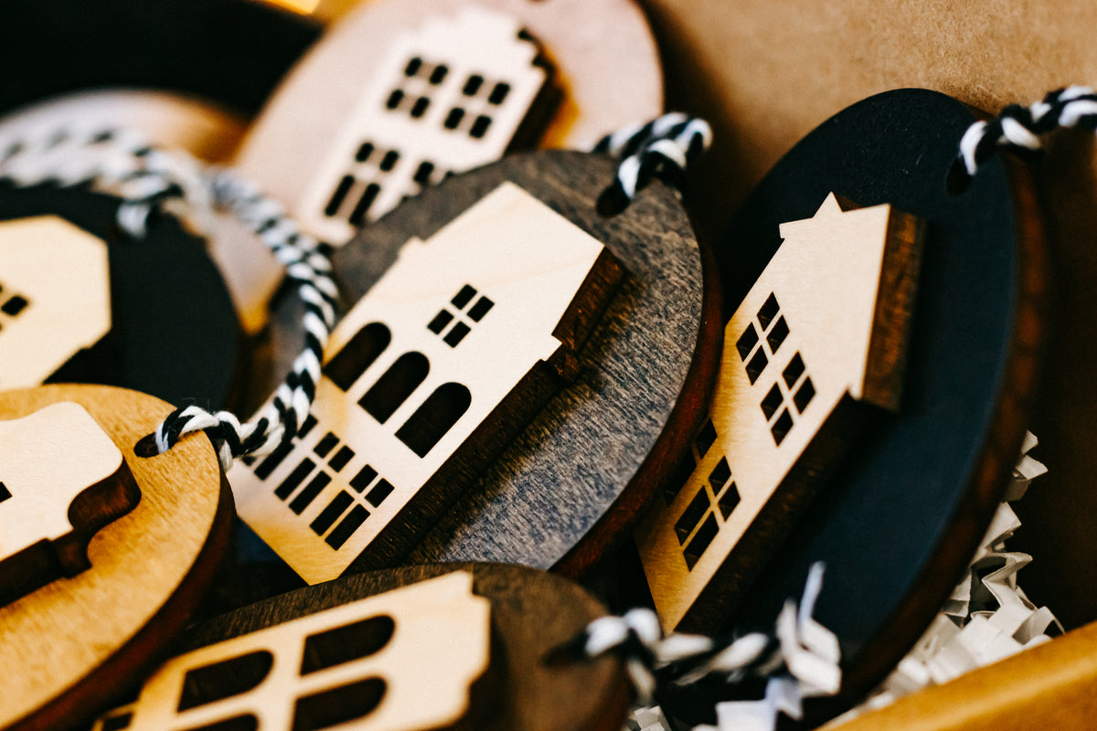 Close-up of round house ornaments in wood and dark finishes, with striped hanging cords