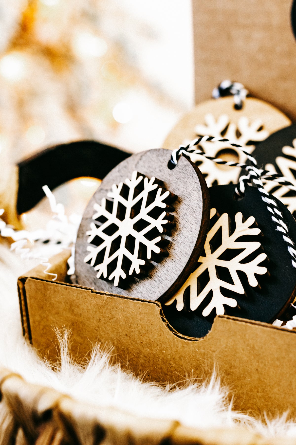 Layered round snowflake ornaments in box: black and light wood with white snowflakes