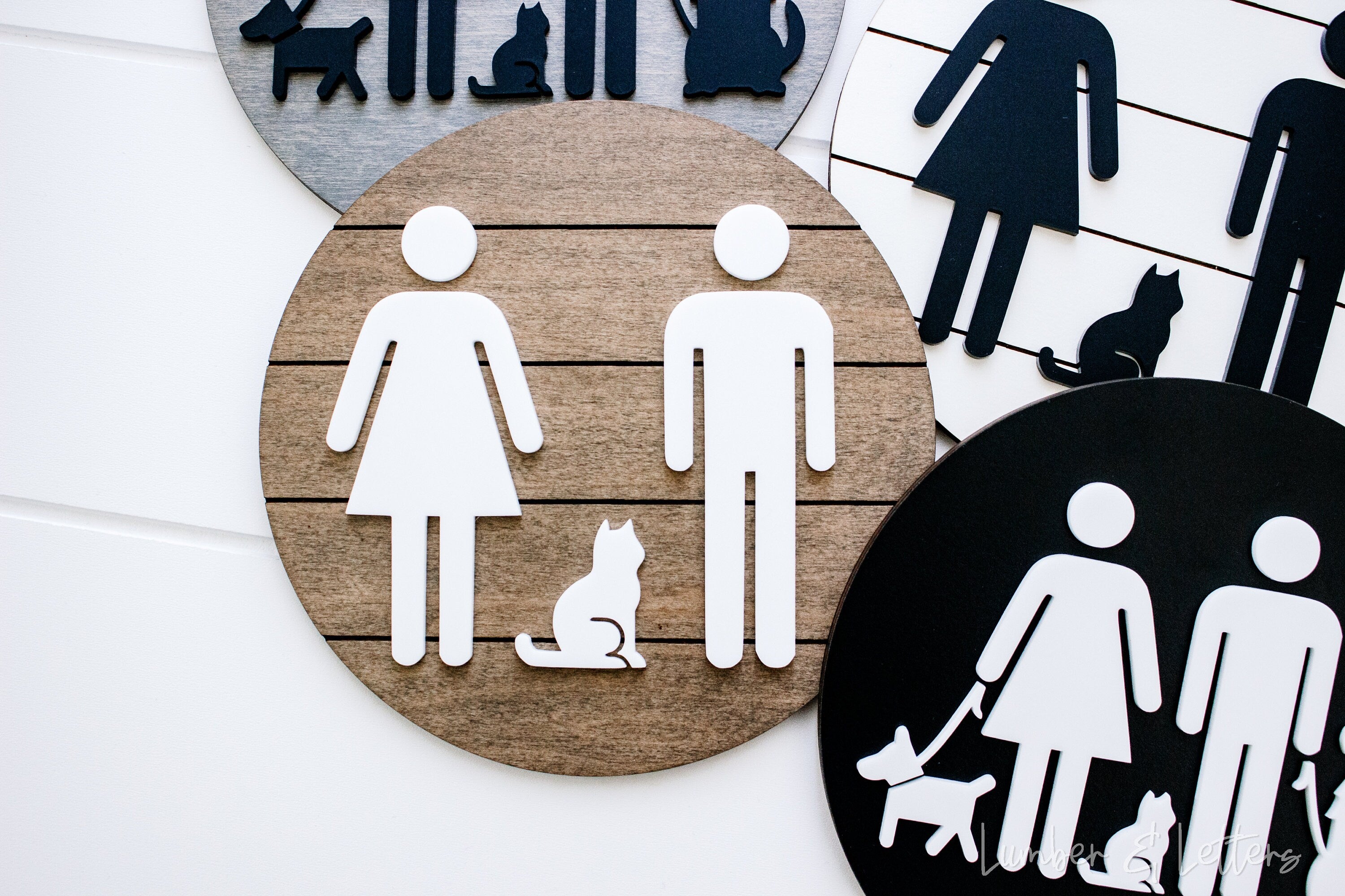 Round restroom sign with pet silhouettes, white icons on tan circle beside a black sign