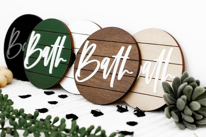 Round bath signs showing multiple “Bath” colors, including black, green, and wood