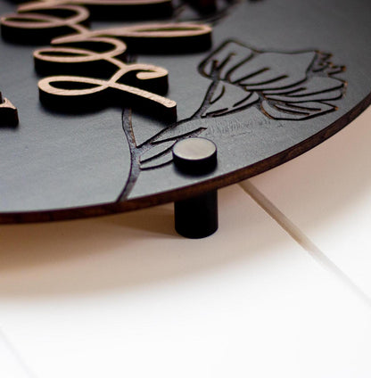 Dark restroom sign panel with raised decorative floral engraving and round stud accents