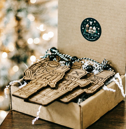 Set of 6 engraved wooden nutcracker ornaments in box with round hanging label and bead cords