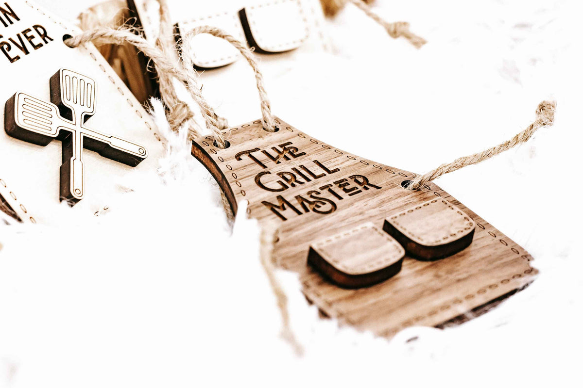 Wood “The Grill Master” ornament with grill-shaped slot pieces and hanging rope.