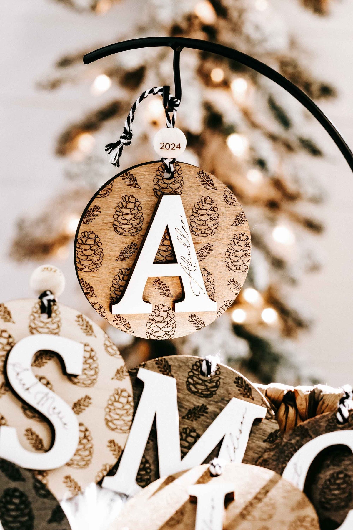 Round engraved pine cone ornament letter A on hoop hanger, year 2024, zebra cord