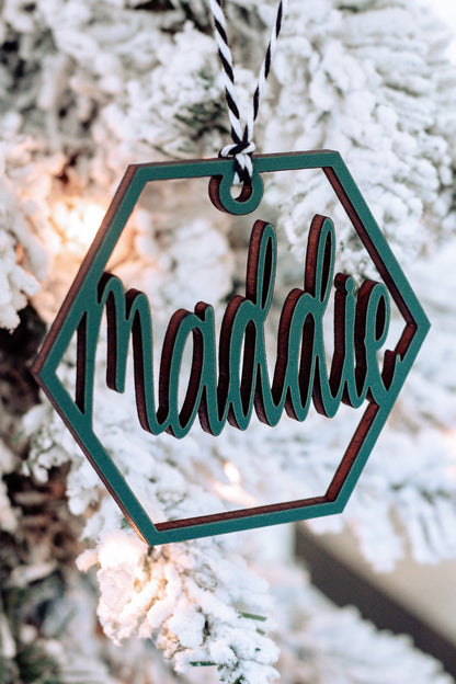 Wooden hex name ornament with teal cursive “Madalie” engraving, twine loop