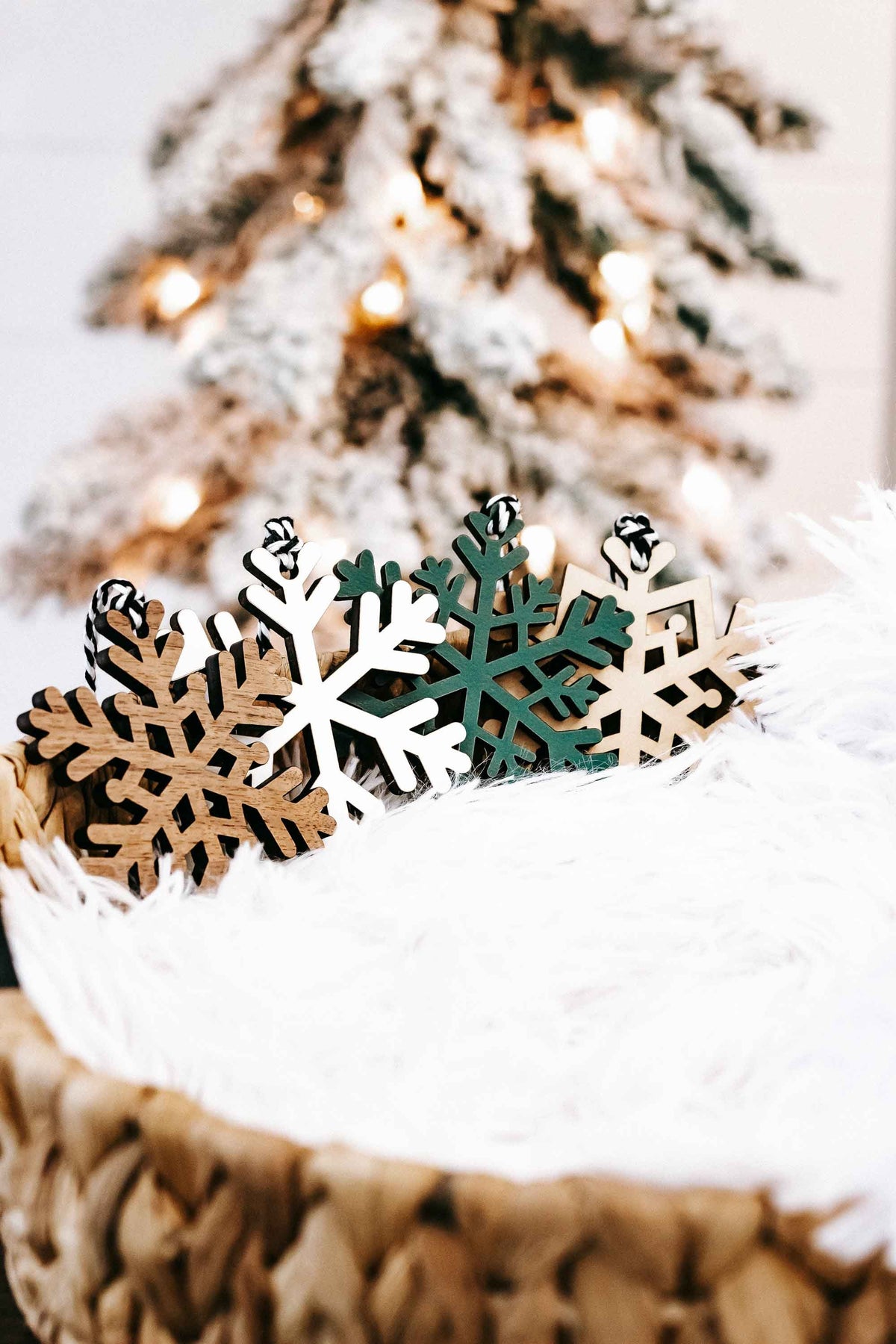 Set of snowflake wood Christmas ornaments on white faux fur in a basket