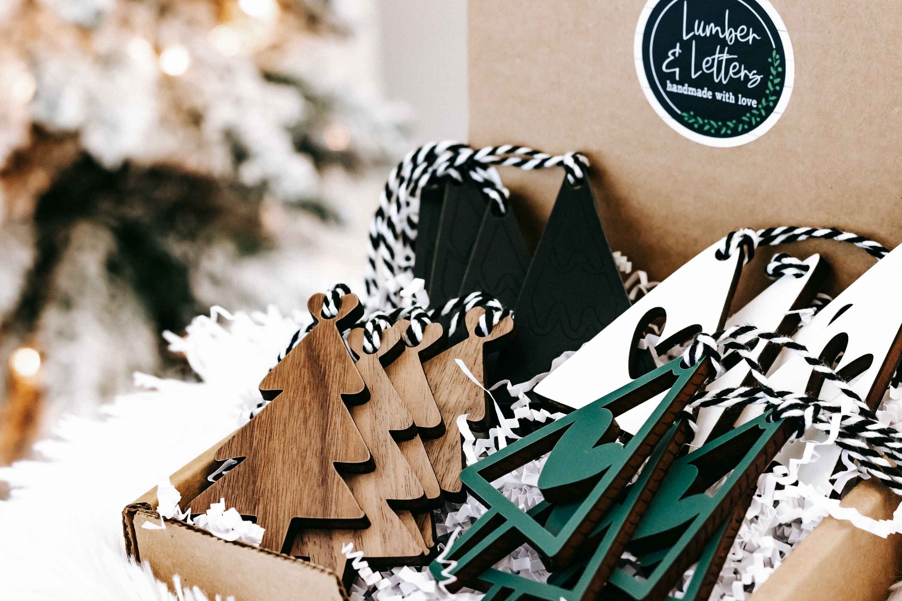 Close view of boxed wooden Christmas ornaments with striped rope hangers and dark green accents