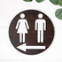 Directional restroom sign with white female icon and left-pointing arrow on dark round backing