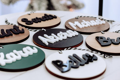Close-up of round wooden name ornaments with rope hangers and dark and white letter designs